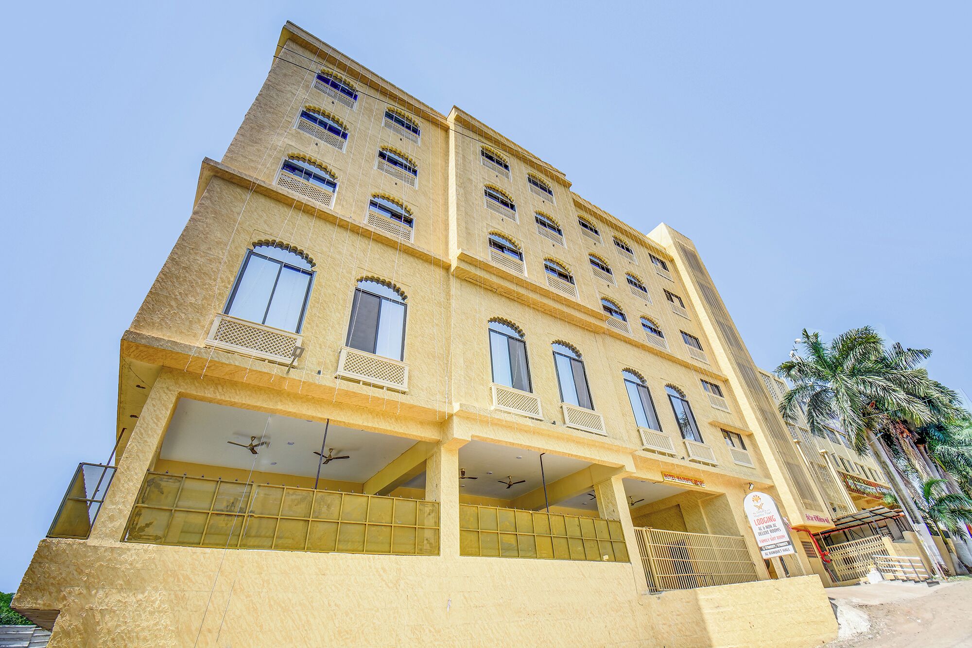 A multi-story building with balconies, a sign indicating lodging, and a clear sky.