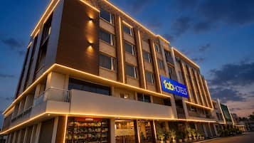 A multi-story hotel with a prominent 'fab hotels' sign, a visible storefront with a 'JOYBEAN' sign, and a modern architectural design with illuminated lines.