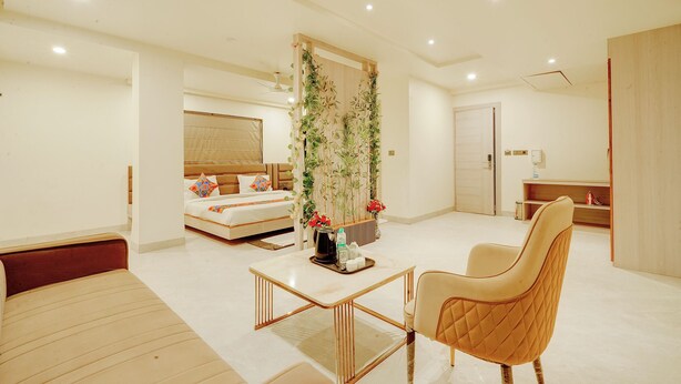 Une chambre d’hôtel moderne comprenant un lit, un coin salon avec une table et une chaise, un mur végétal décoratif et une porte en bois.