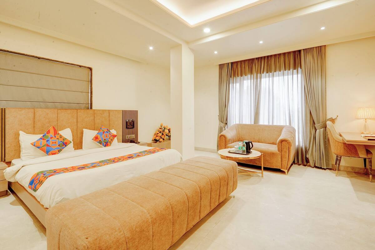 Una habitación de hotel con cama, sofá, mesita y escritorio.