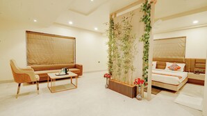 Une chambre d’hôtel moderne avec un canapé, une table basse, un lit et un mur décoratif végétal.