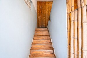 Uma escada de madeira que leva a um quarto com cortina de bambu.