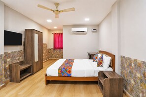 Een slaapkamer met een houten bed, een plafondventilator, een airconditioning en een televisie, met een wand in steenmotief.