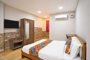 Quarto com cama, guarda-roupa, televisão, ar condicionado e zona de duche.