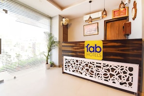 Un mostrador de recepción de hotel con un logotipo, una planta en maceta y un panel decorativo en la pared.