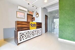 Una recepción con detalles de madera, un letrero de 'fab hotels' y un panel decorativo en la pared.