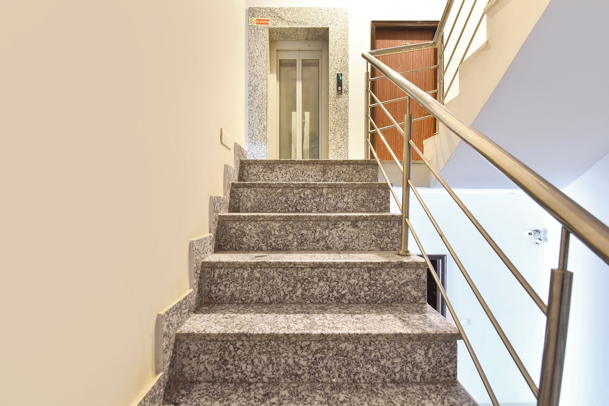 A staircase with granite steps, a handrail, and a door at the top.
