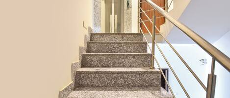 A staircase with granite steps, a handrail, and a door at the top.