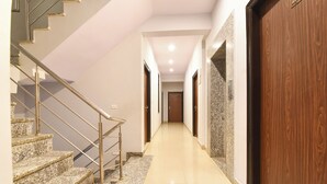 A hallway with a marble staircase, wooden doors, and a polished floor. - FabHotel Blue Diamond - Mansarovar , Jaipur (Jaipur)