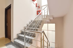 Una escalera con barandillas metálicas, un extintor y una puerta.