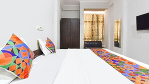 A hotel room with a bed, a desk, a chair, a TV, and a window with curtains. - FabHotel Blue Diamond - Mansarovar , Jaipur (Jaipur)