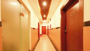 Et hotel med korridor, døre, brandslukker og en lampe i loftet.