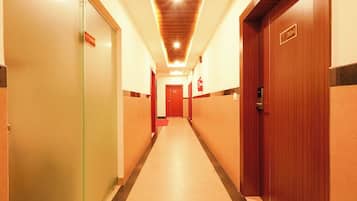 Un pasillo de hotel con puertas, un extintor y una lámpara en el techo.