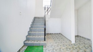 A staircase leading to a landing with white walls and a tiled floor.