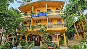 Un hôtel à plusieurs étages, avec une façade jaune, des balcons et une enseigne.
