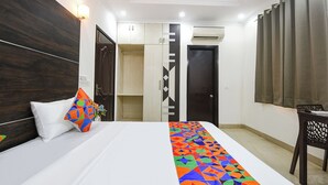 A hotel room with a bed, a desk, a chair, and a wardrobe. - FabHotel Tulip Inn Residency - Mayom Hospital, D-Block, 19 (Gurugram)