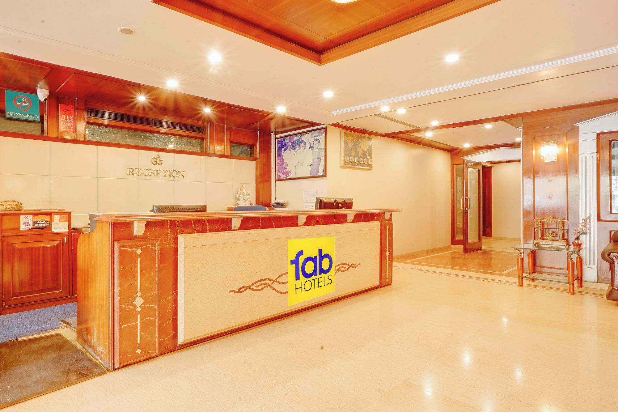 Una mesa de recepción con el logotipo de 'fab hotels', un cartel de 'no fumar' y una cámara de CCTV.