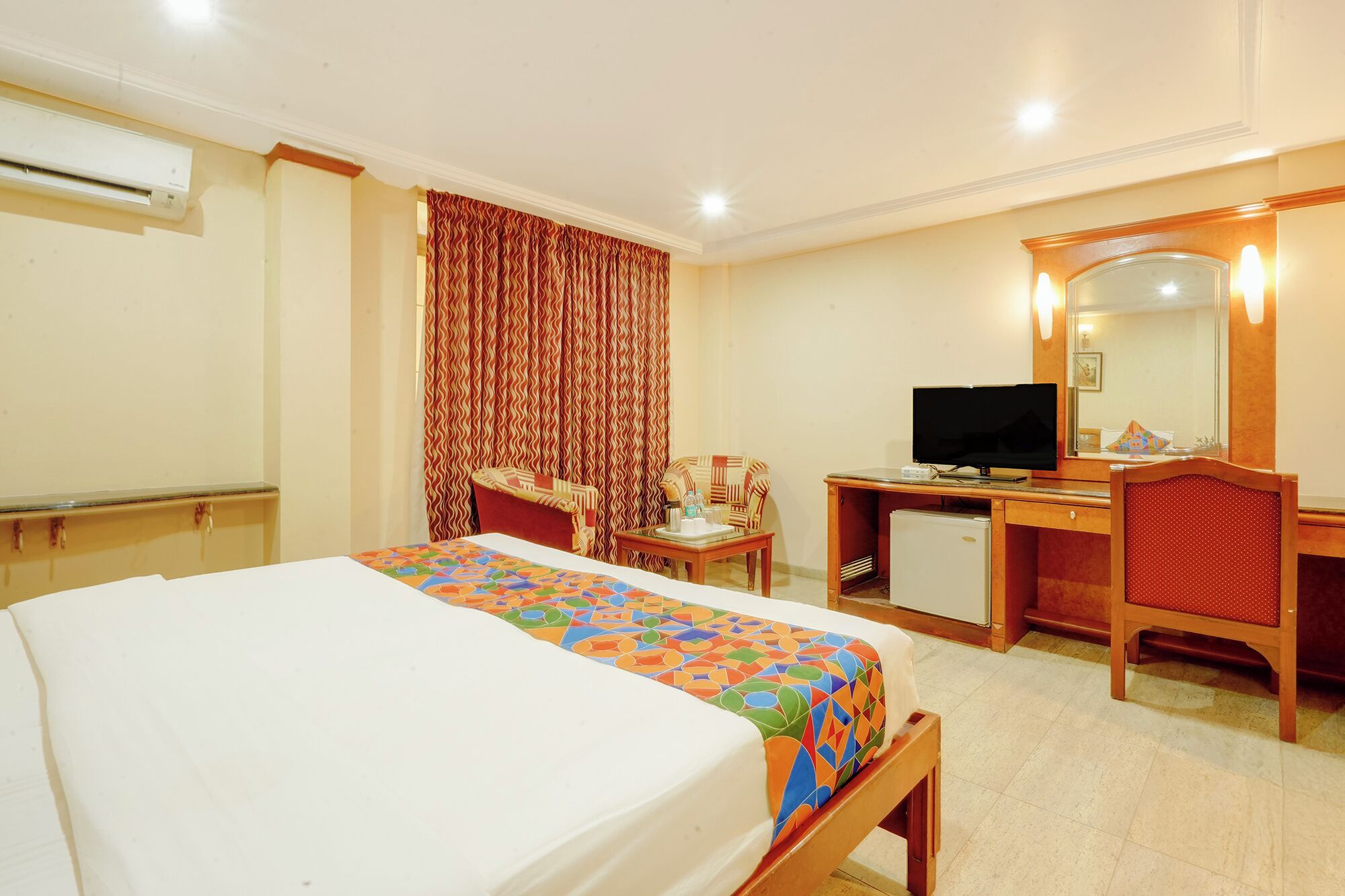 A hotel room with a bed, a desk, a television, and a mirror.