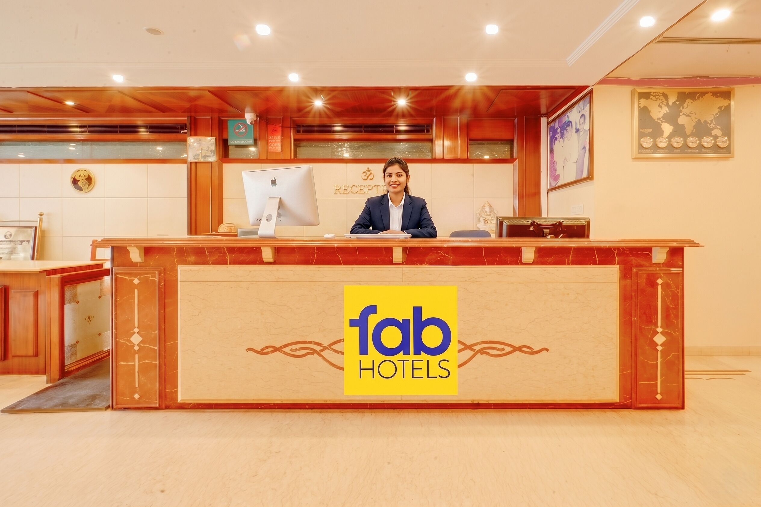 A hotel reception desk with a logo, a computer, and a framed picture on the wall.