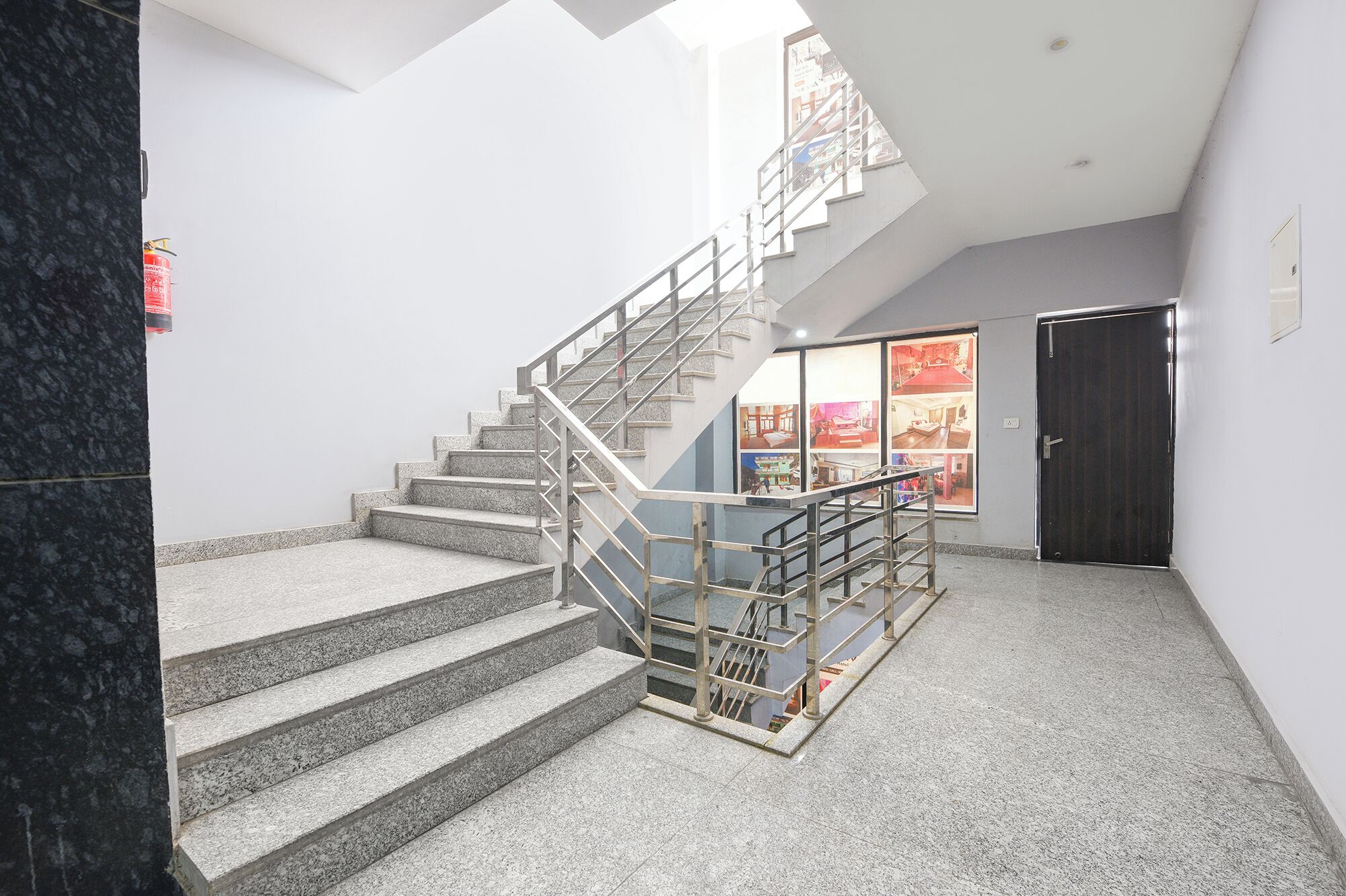 A staircase with metal railings, a dark door, and a window with a view of a room.
