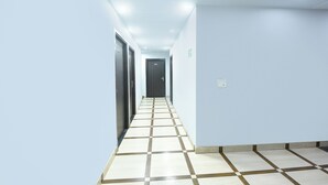 A corridor with a checkered floor, light blue walls, and doors at the end. - FabHotel A V Homes - Navjeevan Hospital & Maternity Centre (Gurugram)
