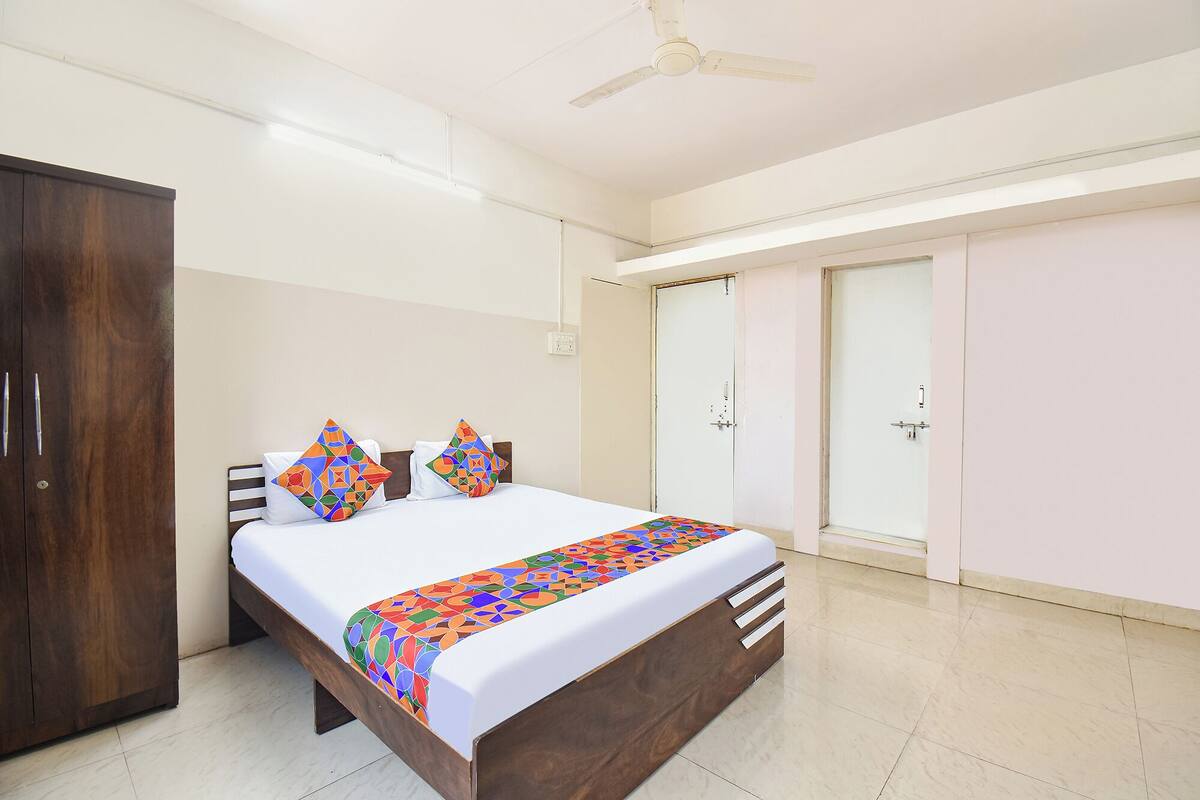 A bedroom with a bed, a wardrobe, a door, and a ceiling fan.