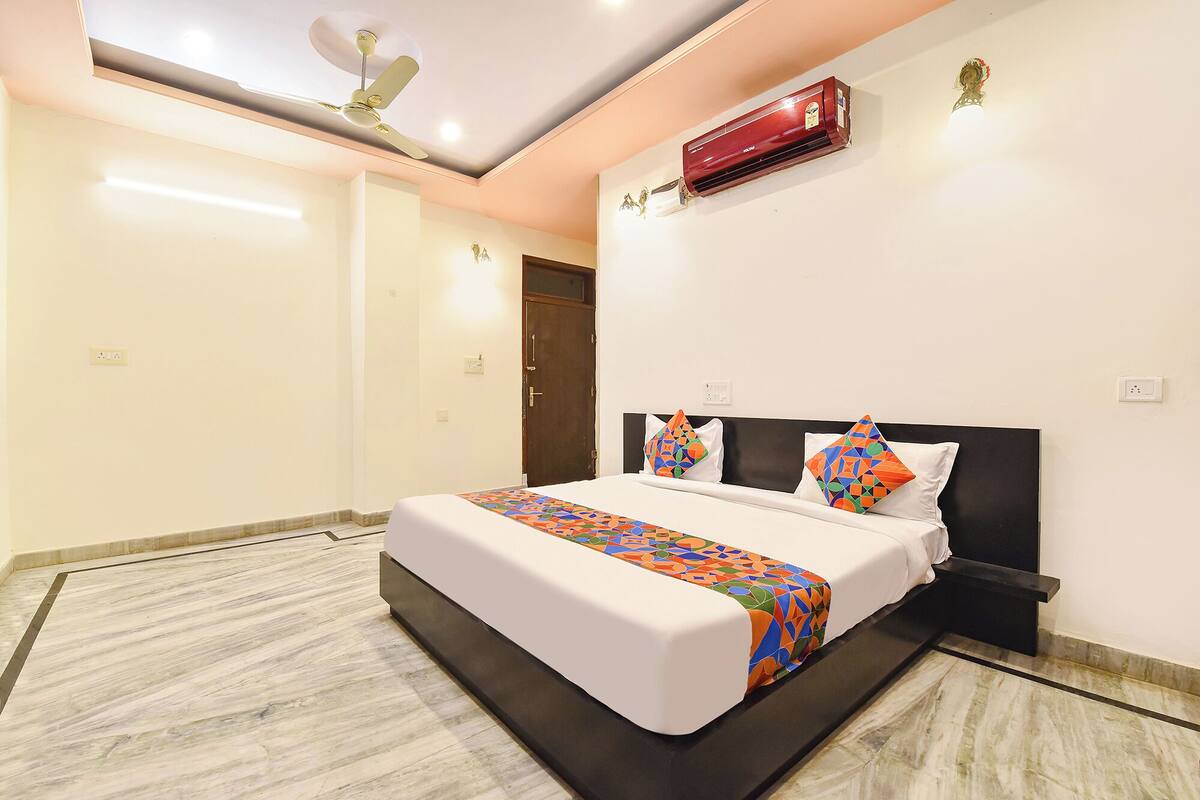 A hotel room with a bed, a ceiling fan, an air conditioning unit, and a marble floor.