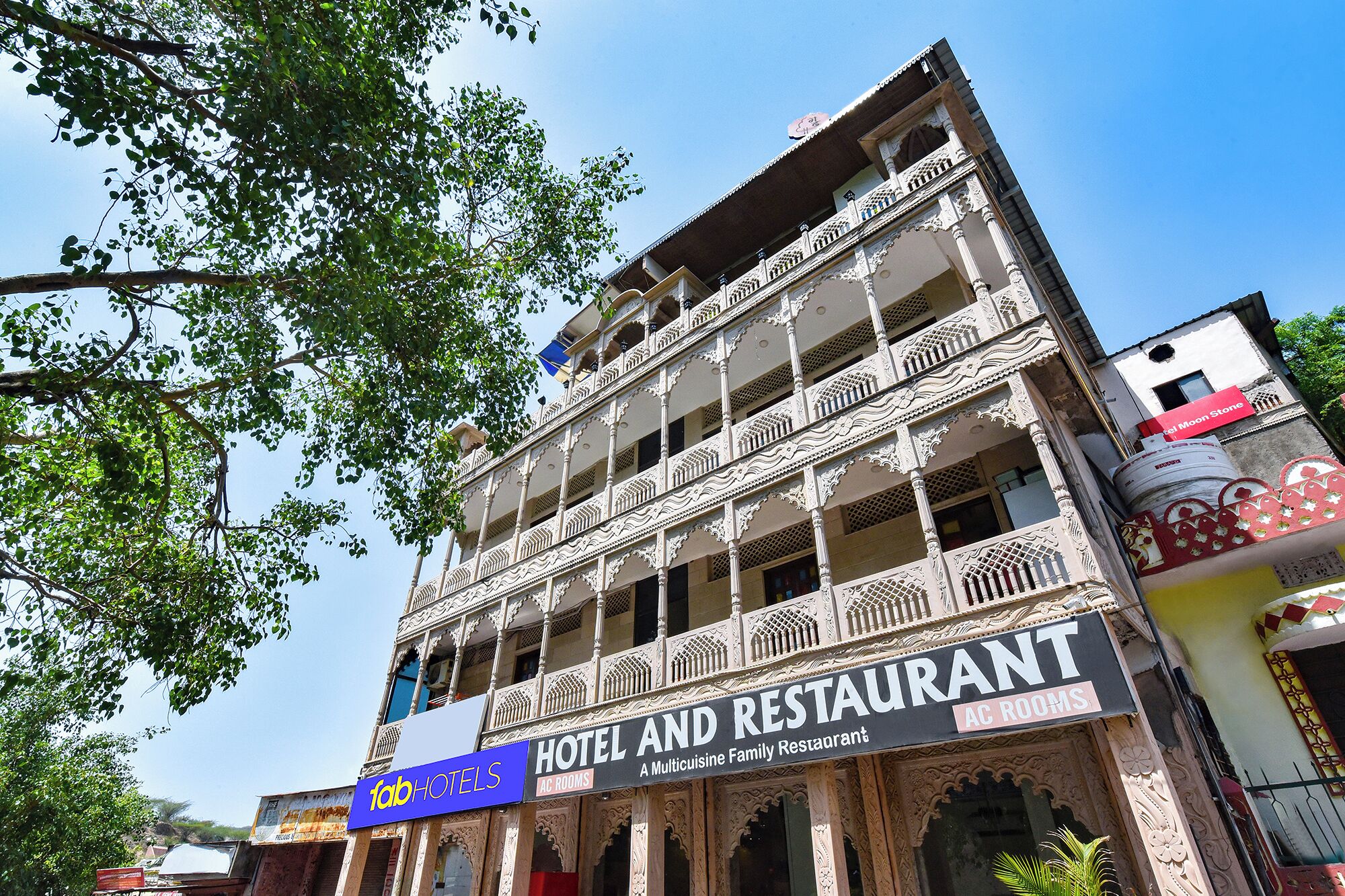 Un hotel de varios pisos con balcones ornamentados y un letrero que dice 'Hotel and Restaurant AC Rooms'.