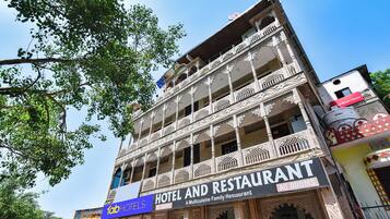 Un hotel de varios pisos con balcones ornamentados y un letrero que dice 'Hotel and Restaurant AC Rooms'.