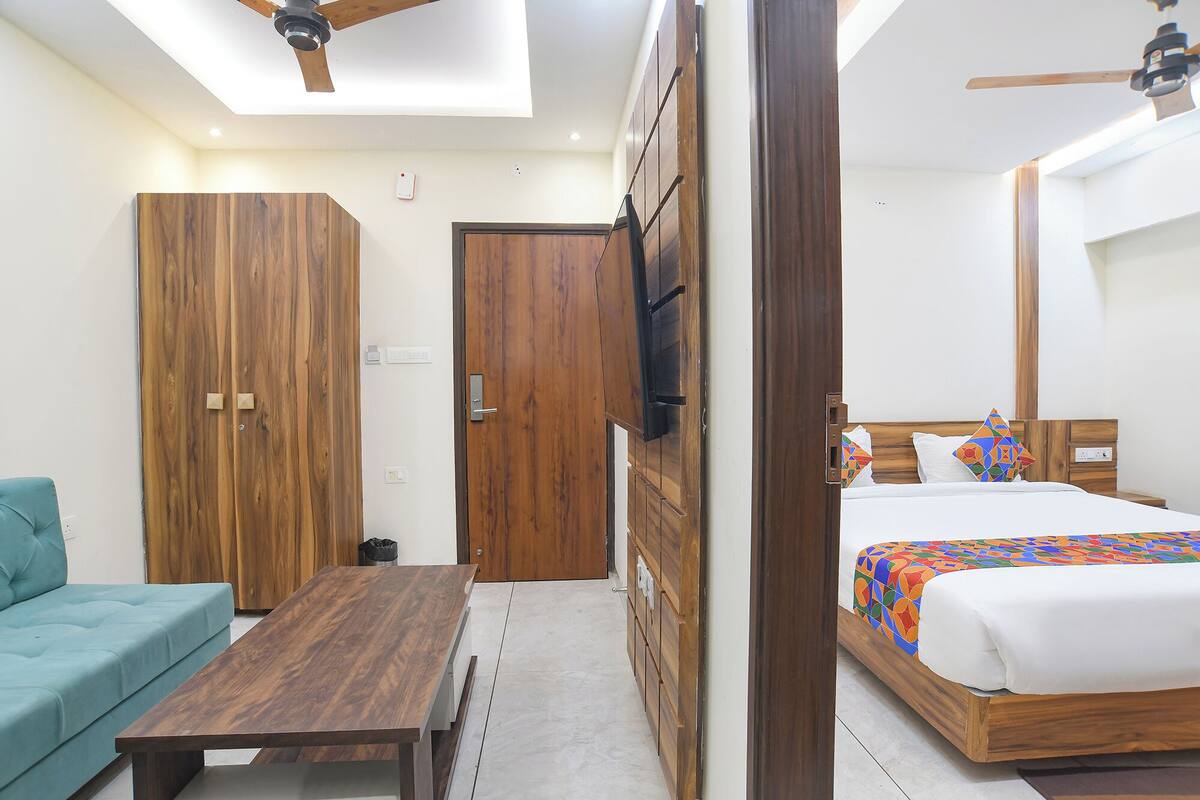 Un dormitorio con cama, sofá, armario de madera, mesa de madera y ventilador de techo.