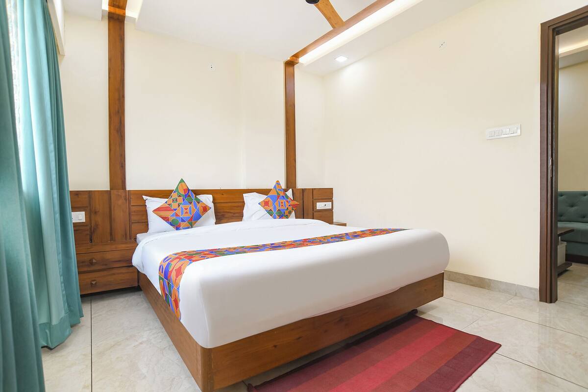 Un dormitorio con una cama de madera, un tapete rojo y una cortina verde.