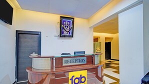 Una reception con un cartello 'fab hotels', un quadro incorniciato sopra e un pavimento a scacchi.