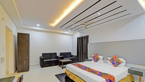 Una camera d'albergo moderna con un letto grande, due poltrone, un tavolino e una ventola a soffitto.