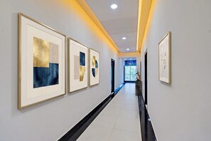 A hallway with framed artworks on the walls, a black strip running down the center, and a window at the end. - FabHotel Prime Palak Residency (Hyderabad)