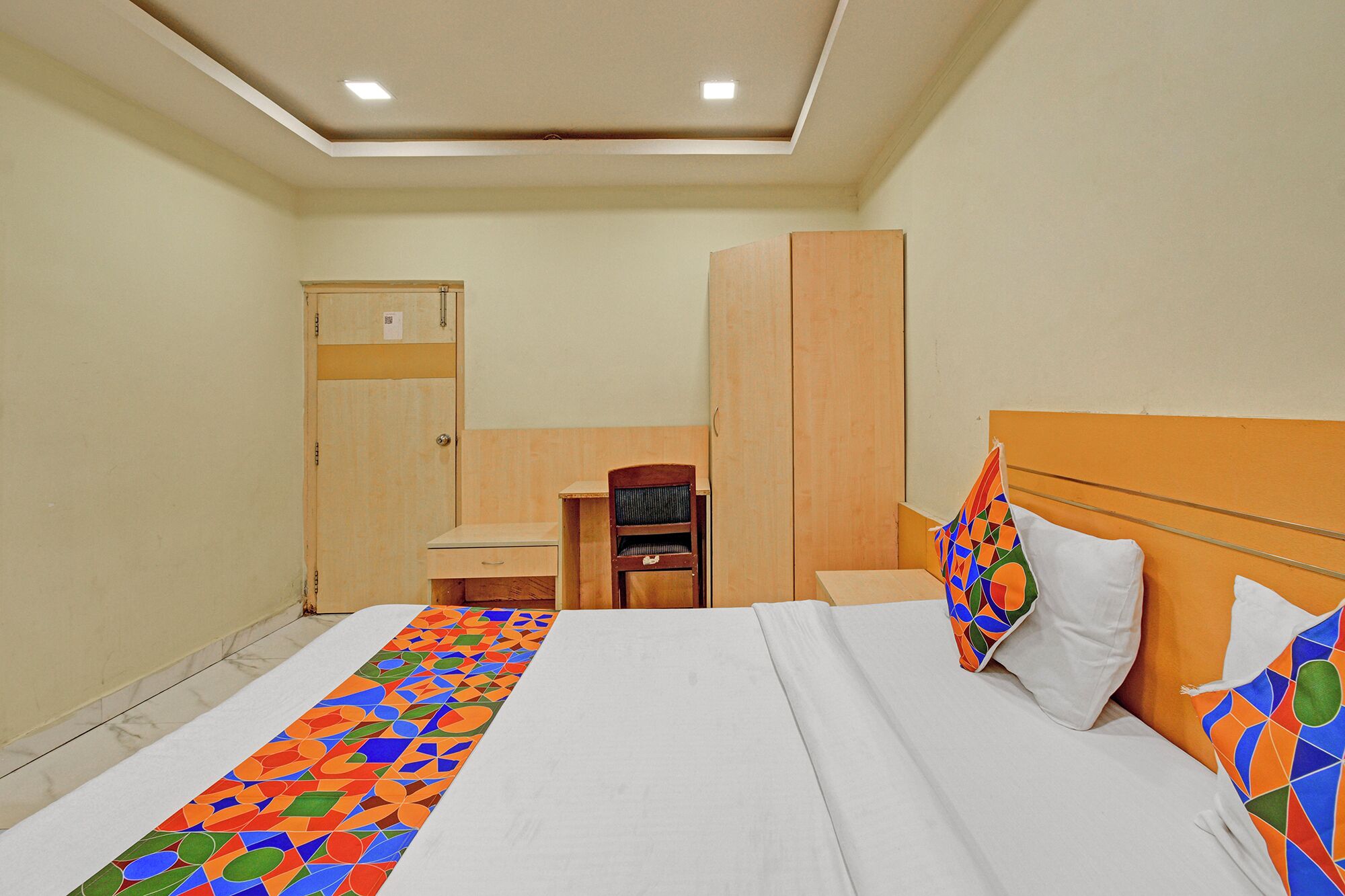 A hotel room with a bed, a desk, a chair, and a wardrobe.