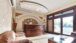 A reception desk, a sofa, a coffee table, and large windows with a view. - Fabhotel Jd Four Boutique (Jaipur)