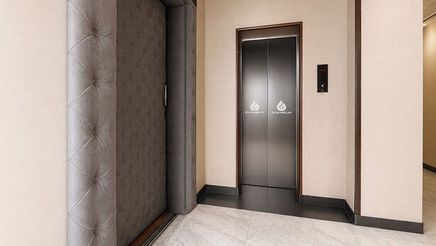 A hallway with a tufted wall, a door with a 'FLAMEUP' sign, and a marble floor. - Fabhotel Jd Four Boutique (Jaipur)
