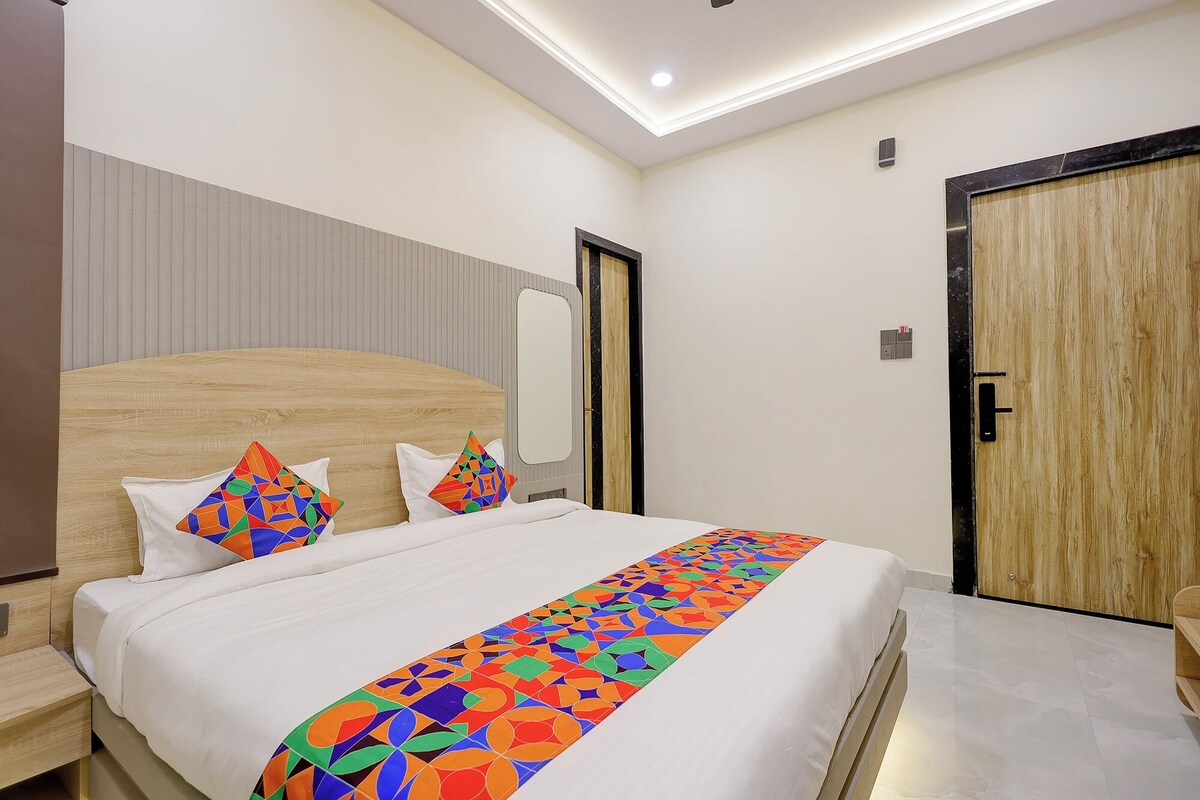A hotel room with a bed, a nightstand, a wooden headboard, a mirror, and a wooden door.