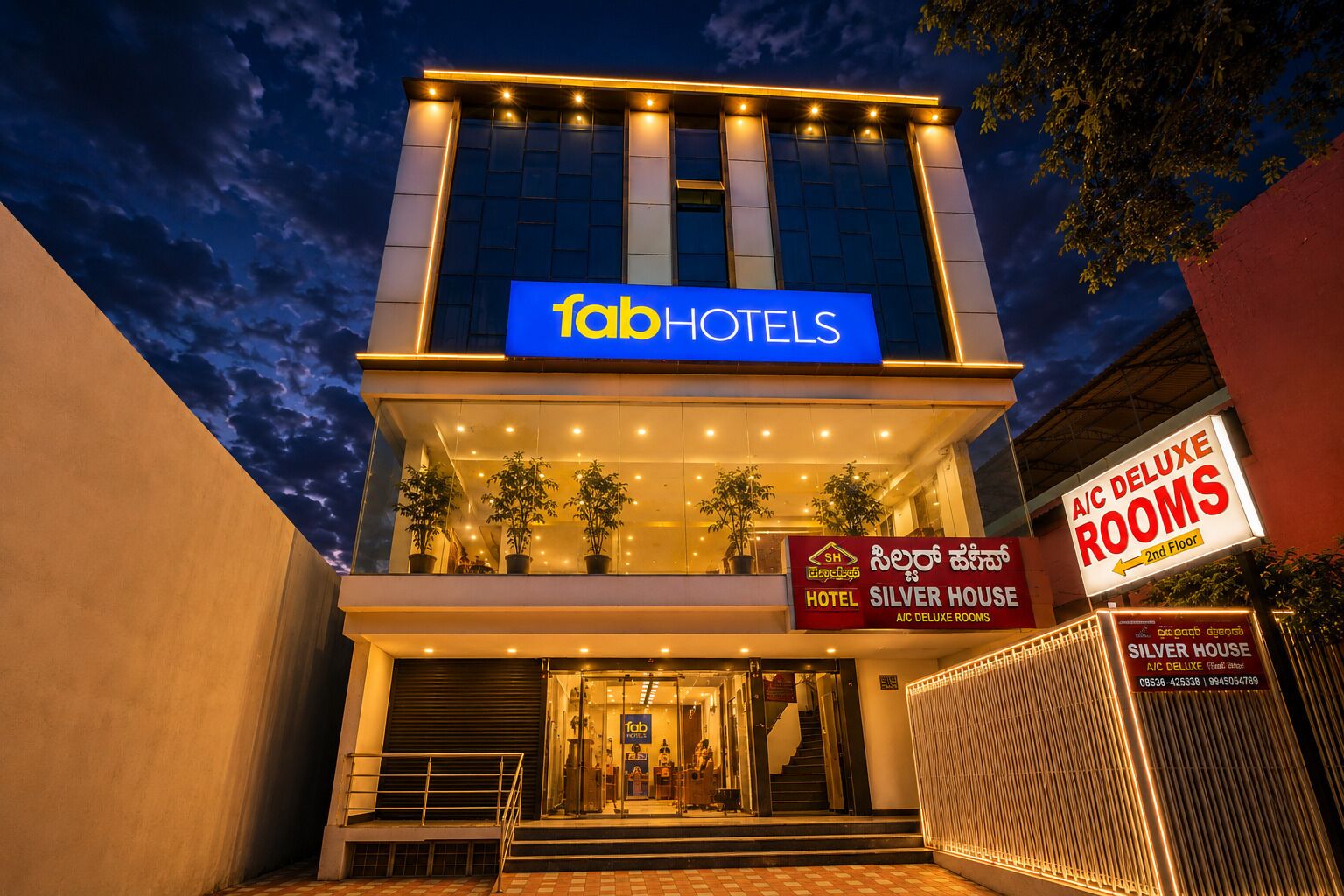 A modern building with a sign for fab hotels. There are potted plants on the balcony, and a staircase leading to the entrance.