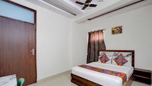 Une chambre avec un lit en bois, un ventilateur de plafond, une porte et une petite table.
