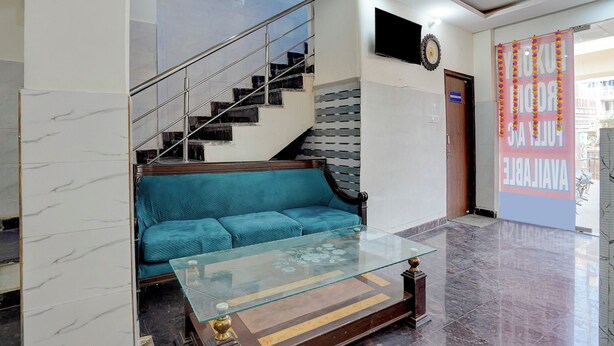 Un hall d’entrée avec un escalier, un canapé, une table basse en verre et un téléviseur fixé au mur.