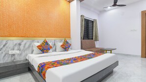 A modern bedroom with a bed, a ceiling fan, a window with curtains, and a small table. - FabHotel Ambrosia Seventy Eight (Indore)