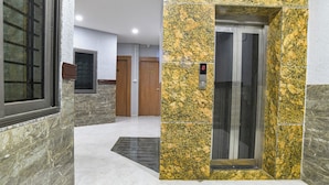 A modern elevator with a digital display, a stone wall with a marble pattern, and a door with a number sign. - FabHotel Ambrosia Seventy Eight (Indore)