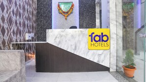 A reception desk with a marble counter, a 'fab hotels' sign, and a decorative garland. - FabHotel Ambrosia Seventy Eight (Indore)