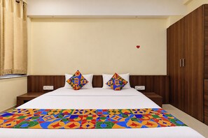 A hotel room with a bed, two nightstands, a wooden wardrobe, and a colorful bedspread. - FabHotel La Banian (Indore)