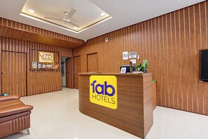 A hotel reception desk with a wooden finish, a ceiling fan, and a sign for 'Tab Hotels'. - FabHotel La Banian (Indore)