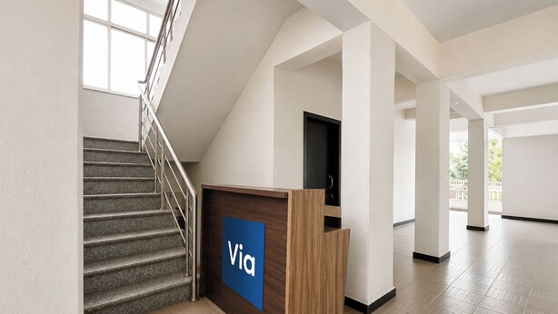 A modern interior with a staircase, a reception desk labeled 'Via,' and a large window. - Via Dazling Studio (Pune)