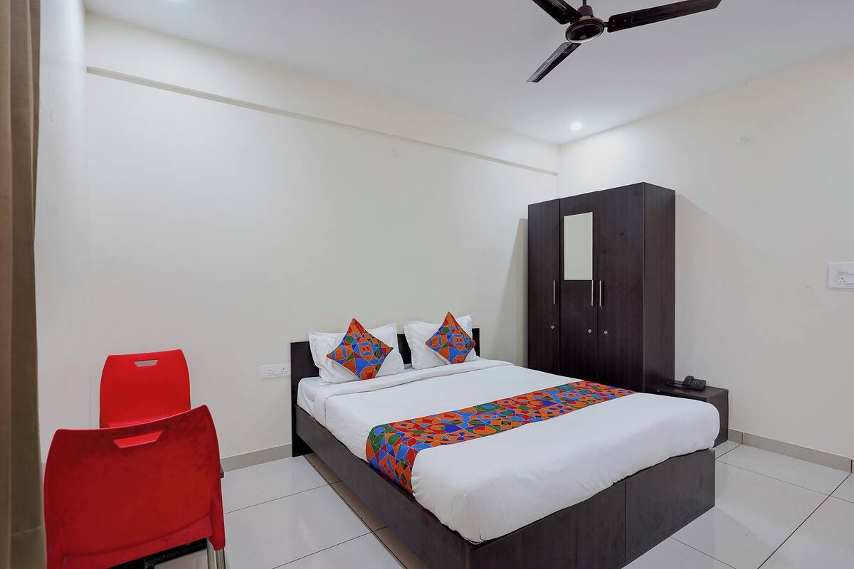 A bedroom with a bed, a wardrobe, a red chair, and a ceiling fan.