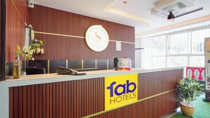 En receptionsdisk med et ur, et skilt med 'fab hotels' og en potteplante.