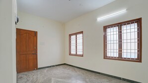 Un pasillo con una puerta de madera, una ventana con barrotes y un suelo de baldosas.